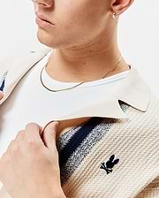 Mens Giles Relaxed Fit Border Knit Shirt in cream textured knit with navy and light blue stripes, featuring a small embroidered navy Psycho Bunny skull logo on the left chest.