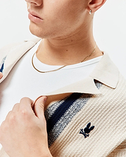 Mens Giles Relaxed Fit Border Knit Shirt in cream textured knit with navy and light blue stripes, featuring a small embroidered navy Psycho Bunny skull logo on the left chest.