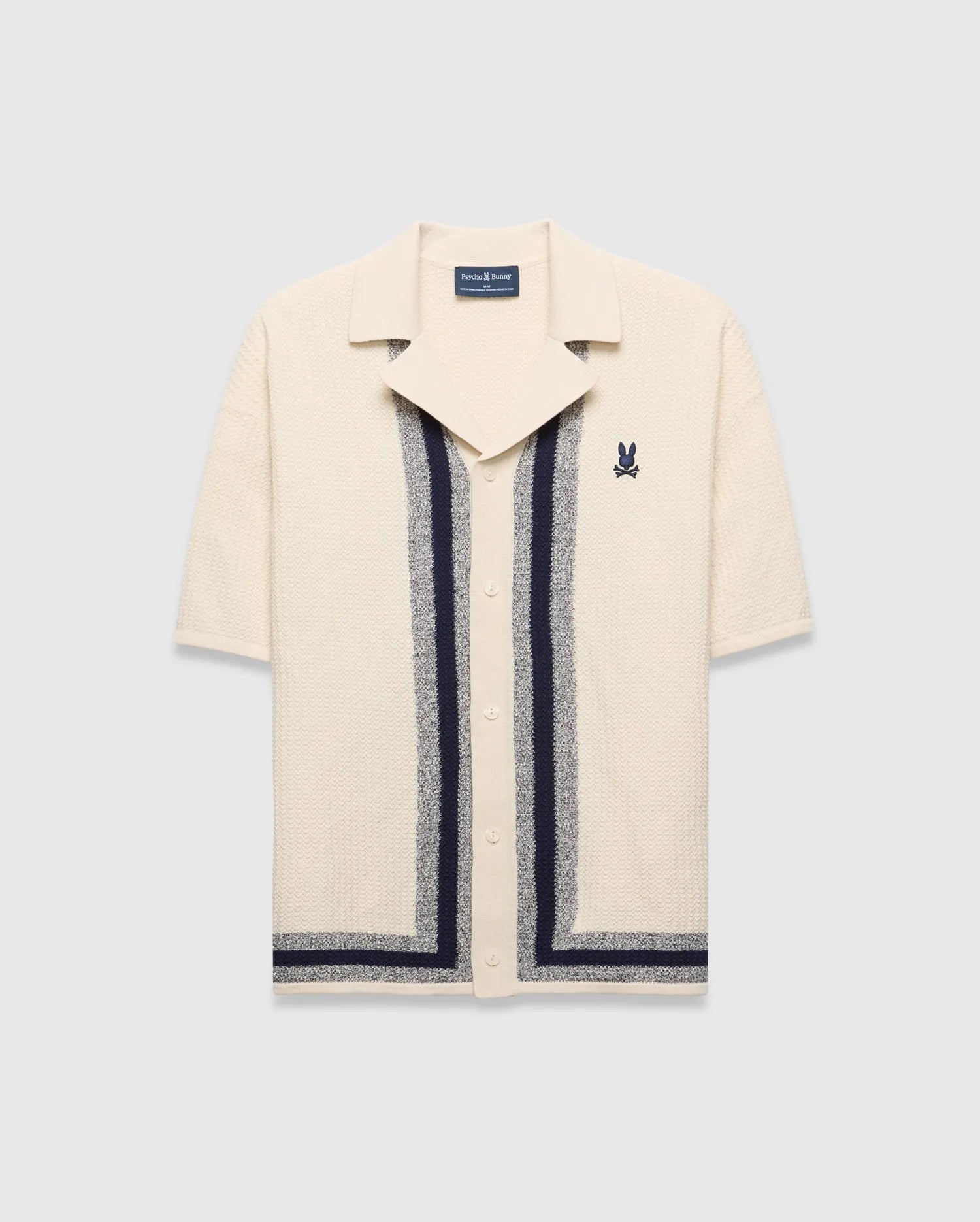 Mens Giles Relaxed Fit Border Knit Shirt in cream textured knit, featuring navy and heather grey vertical stripes, a spread collar, and a small embroidered Psycho Bunny skull on the left chest.