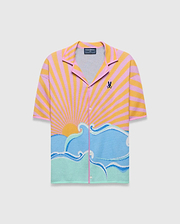 Mens Ray Relaxed Fit Jacquard Shirt featuring a vibrant pink and yellow striped sunset graphic transitioning to blue and mint green ocean waves, with a small embroidered Psycho Bunny skull logo on the left chest.