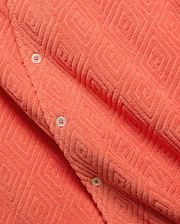 Mens Tristan Shirt, a bold coral plush terry cloth button-up featuring a distinctive raised geometric diamond pattern and contrasting white buttons.