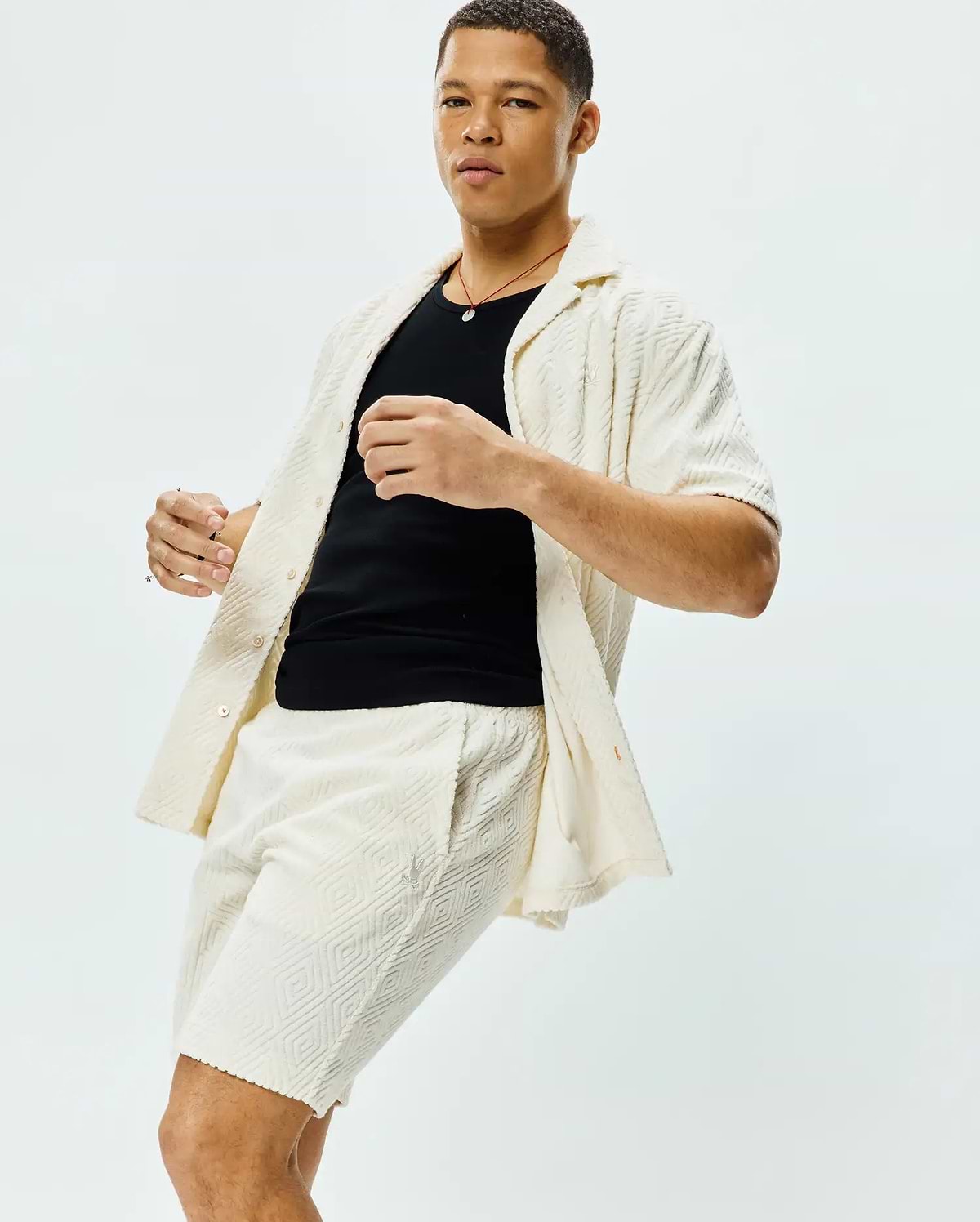 Mens Tristan Shirt: Relaxed fit cream short-sleeve button-up shirt and matching shorts, both featuring a textured geometric diamond pattern and a small embroidered Psycho Bunny skull logo on the shorts.