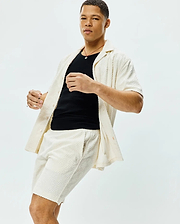 Mens Tristan Shirt: Relaxed fit cream short-sleeve button-up shirt and matching shorts, both featuring a textured geometric diamond pattern and a small embroidered Psycho Bunny skull logo on the shorts.