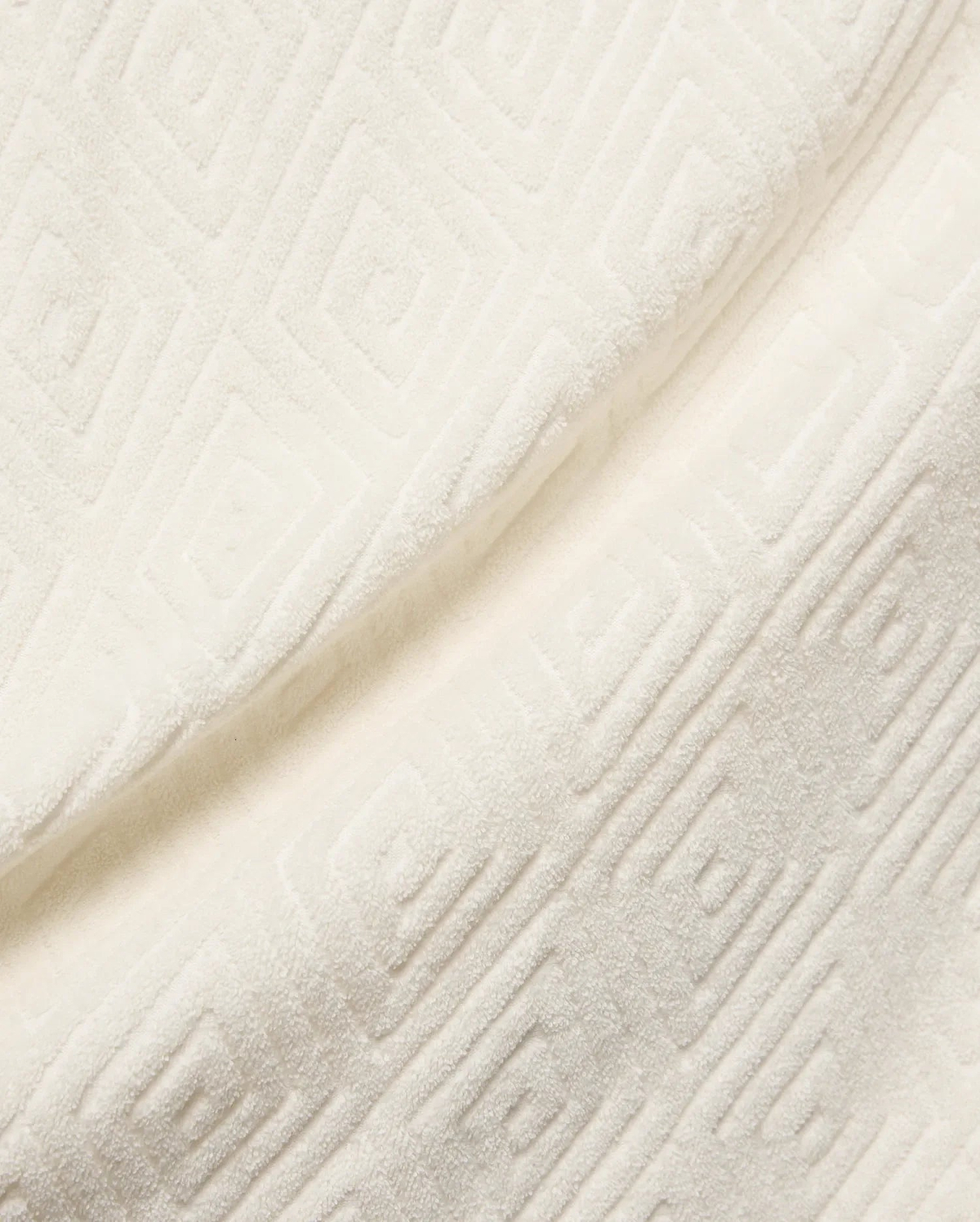 Mens Tristan Shirt in cream, a plush, textured jacquard fabric with an embossed interlocking geometric square pattern, reflecting Psycho Bunny's refined streetwear.