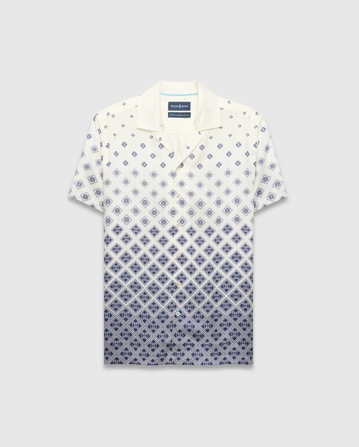 Mens Tobias Tencel Shirt, a relaxed fit cream short-sleeve camp collar shirt with a navy blue diamond pattern that intensifies downwards, featuring the iconic Psycho Bunny skull logo.