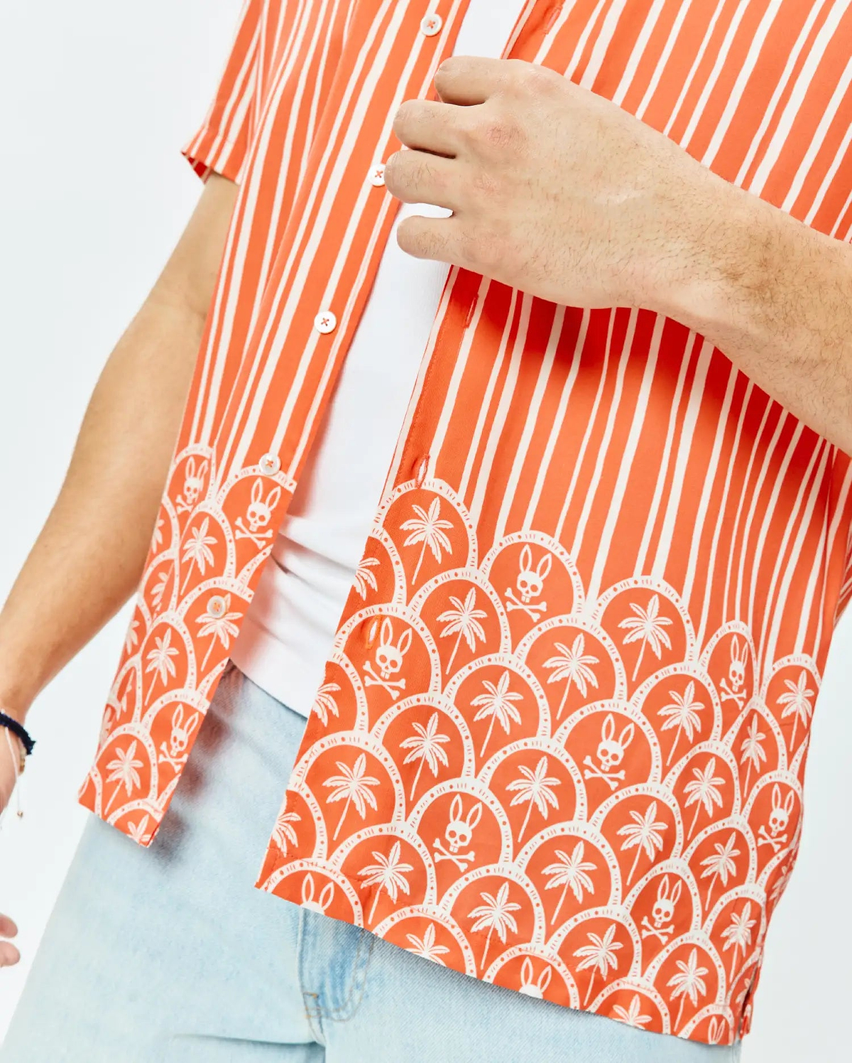 Mens Brad Tencel Shirt, an orange and white striped short-sleeve shirt with a relaxed fit, featuring a lower scalloped pattern of white palm trees and Psycho Bunny skull logos on smooth Tencel fabric.