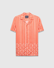 Coral orange Mens Brad Tencel Shirt, a relaxed fit camp collar shirt with white vertical stripes. The lower hem features a white scalloped pattern incorporating palm trees and small Psycho Bunny skull logos.