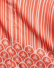 Mens Brad Tencel Shirt in coral with white vertical stripes and a bottom border featuring white palm trees and Psycho Bunny skull logos in a scalloped pattern, with white buttons.