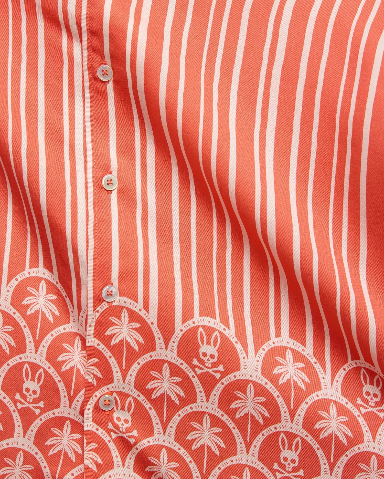 Mens Brad Tencel Shirt in coral with white vertical stripes and a bottom border featuring white palm trees and Psycho Bunny skull logos in a scalloped pattern, with white buttons.