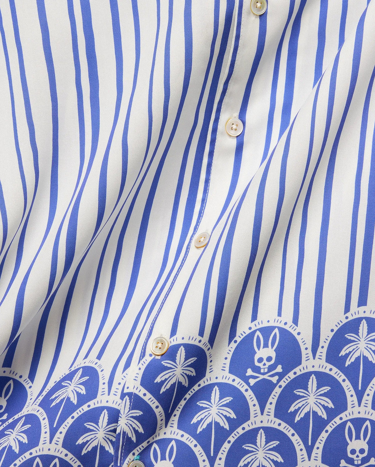 Mens Brad Tencel Shirt featuring a white and royal blue vertical stripe pattern, transitioning to a decorative border with repeating palm trees and the iconic Psycho Bunny skull logo on smooth Tencel fabric.