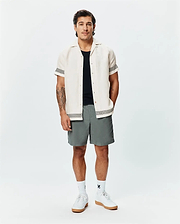 Mens Sunny Linen Shirt, cream, with black zigzag trim on sleeves and hem, paired with grey shorts featuring a small Psycho Bunny logo, white crew socks, and white sneakers.