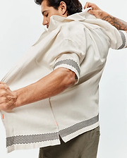 Mens Sunny Linen Shirt, an off-white relaxed-fit short-sleeve shirt with a black zigzag pattern on cuffs and hem, featuring a subtle orange side slit detail and breathable linen texture.