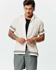 Mens Sunny Linen Shirt, off-white, relaxed fit, with a textured linen fabric, featuring black zigzag patterns on short sleeves and hem, plus a small embroidered Psycho Bunny skull logo on the left chest.