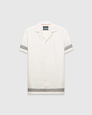 Mens Sunny Linen Shirt, an off-white relaxed linen camp collar shirt, features black zigzag patterns on sleeves and hem, an embroidered Psycho Bunny logo left chest, and orange collar trim.