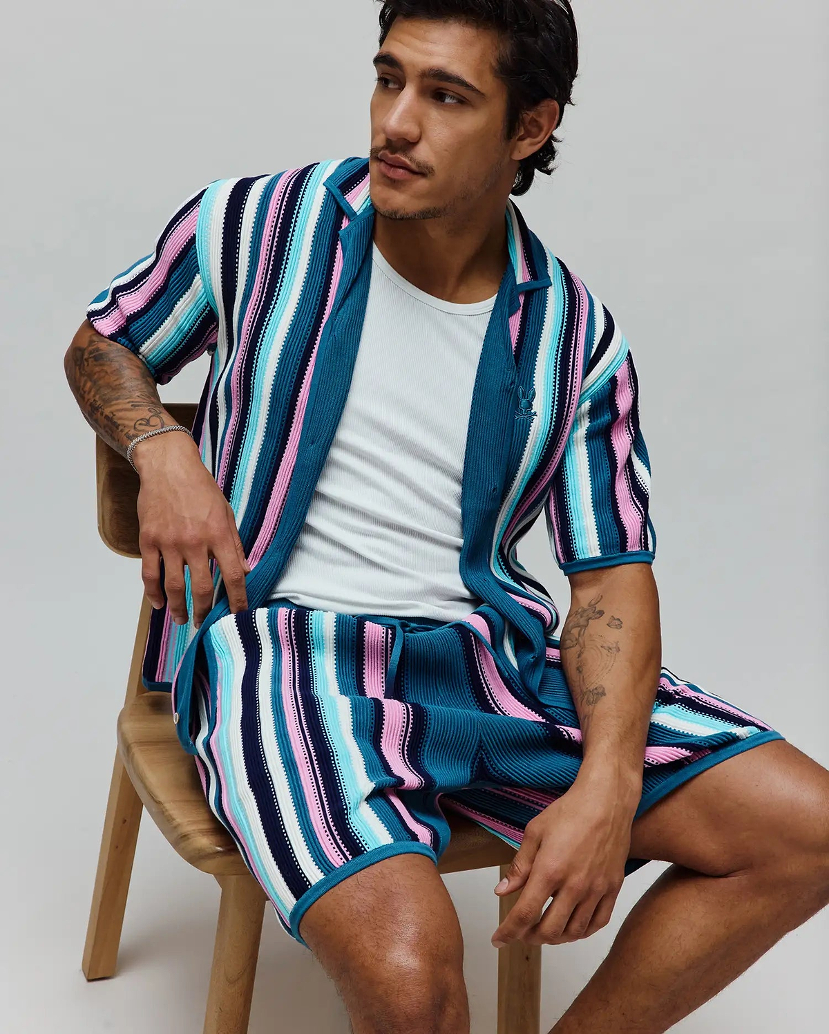 MENS CLIFF SHIRT, a relaxed fit, ribbed knit short-sleeve shirt with bold vertical stripes in teal, pink, light blue, white, and navy, featuring a small embroidered Psycho Bunny skull logo on the chest.