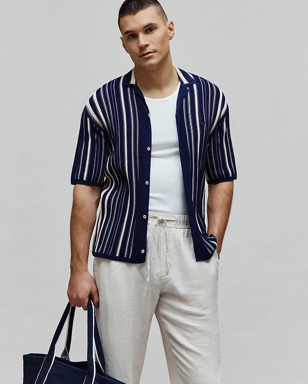 Mens Cliff Shirt, a navy blue knitted short-sleeve button-up shirt with white vertical stripes, an open collar, and a small embroidered Psycho Bunny skull logo on the left chest.