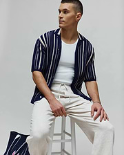 Mens Cliff Shirt: Navy blue textured knit short-sleeve shirt with varied cream vertical stripes, a relaxed fit, and a small embroidered Psycho Bunny skull logo on the left sleeve.