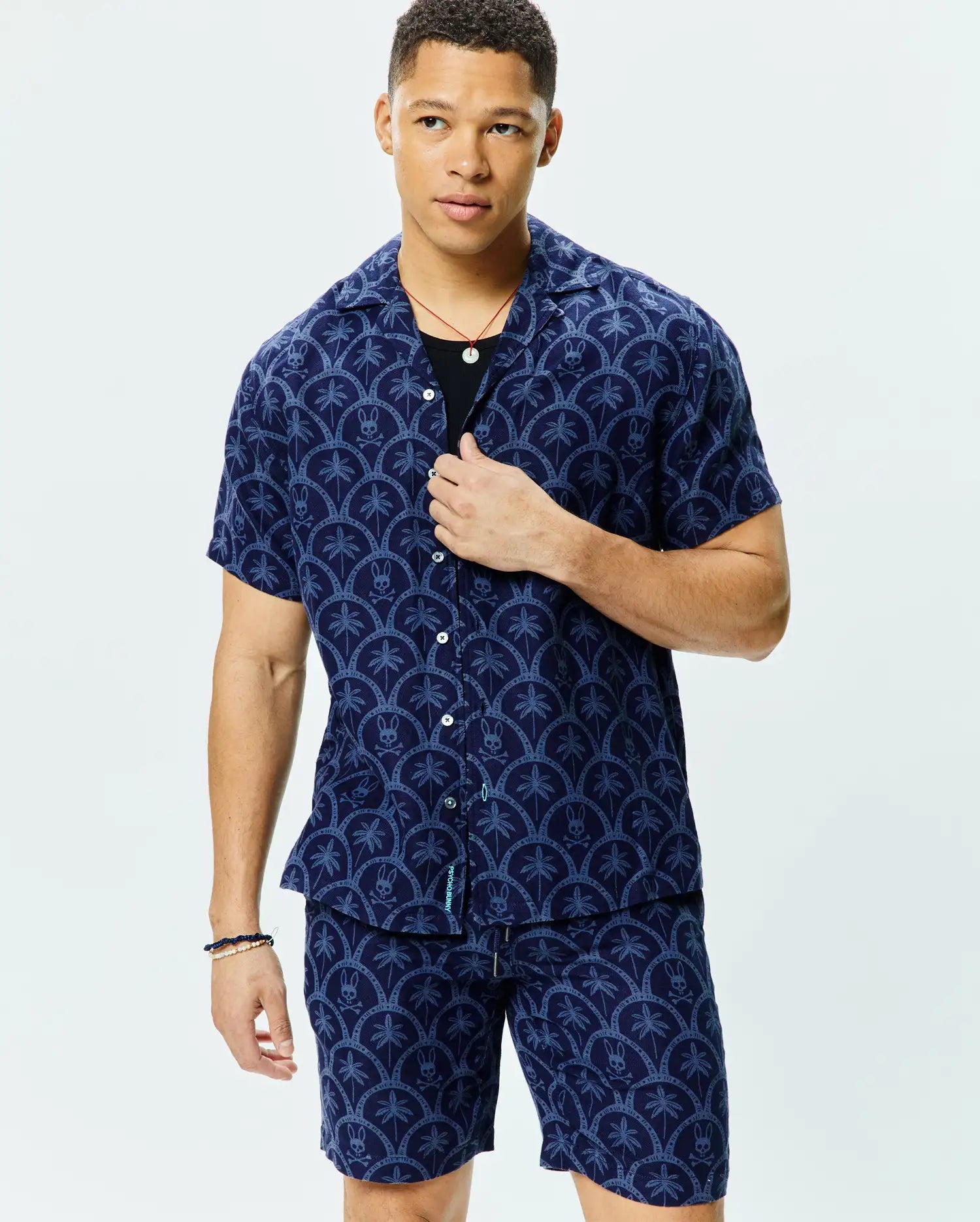 Mens Brad All Over Print Linen Blend Shirt in navy with a light blue all-over scalloped pattern featuring palm trees and small Psycho Bunny skull logos, a relaxed fit, and a camp collar.
