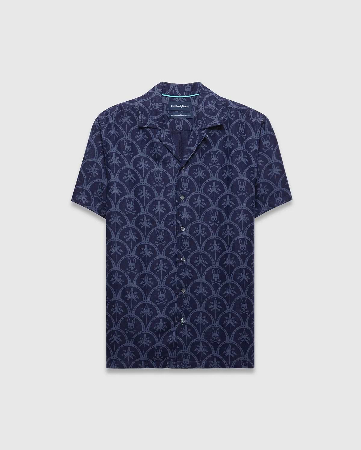 Mens Brad All Over Print Linen Blend Shirt in dark navy with a light blue repeating pattern of palm trees and small Psycho Bunny skull logos, featuring a relaxed fit and camp collar.