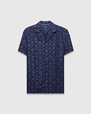 Mens Brad All Over Print Linen Blend Shirt in dark navy with a light blue repeating pattern of palm trees and small Psycho Bunny skull logos, featuring a relaxed fit and camp collar.