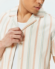 Mens Antoine Shirt: Cream textured short-sleeve camp collar shirt with vertical stripes in orange, light blue, and yellow, featuring a small embroidered Psycho Bunny skull logo on the left chest.