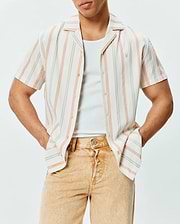 Mens Antoine Shirt, a relaxed fit cream short-sleeve button-up in textured slub fabric with vertical blue, orange, and yellow stripes, featuring a small embroidered Psycho Bunny logo on the left chest.
