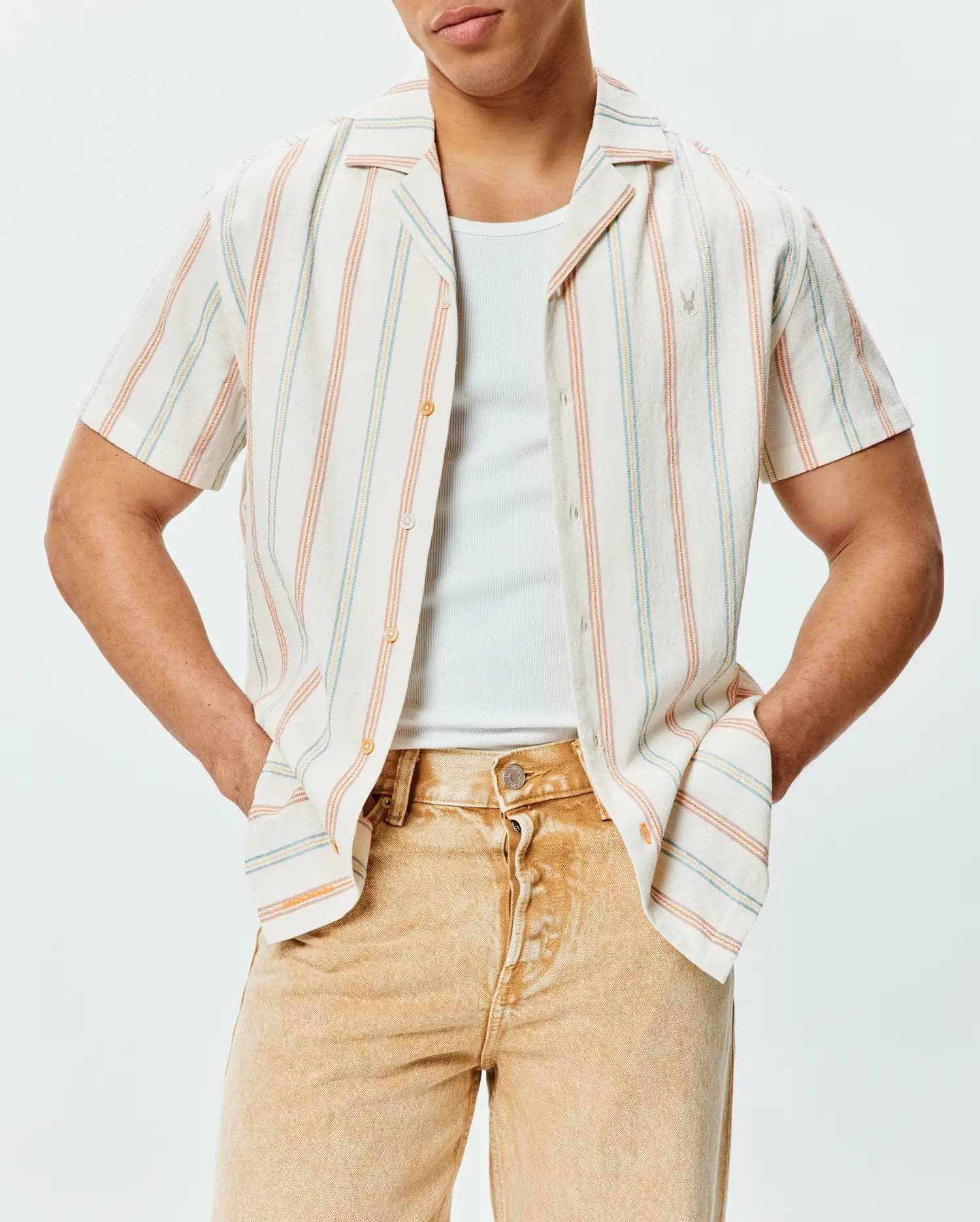 Mens Antoine Shirt, a relaxed fit cream short-sleeve button-up in textured slub fabric with vertical blue, orange, and yellow stripes, featuring a small embroidered Psycho Bunny logo on the left chest.