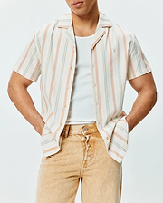 Mens Antoine Shirt, a relaxed fit cream short-sleeve button-up in textured slub fabric with vertical blue, orange, and yellow stripes, featuring a small embroidered Psycho Bunny logo on the left chest.