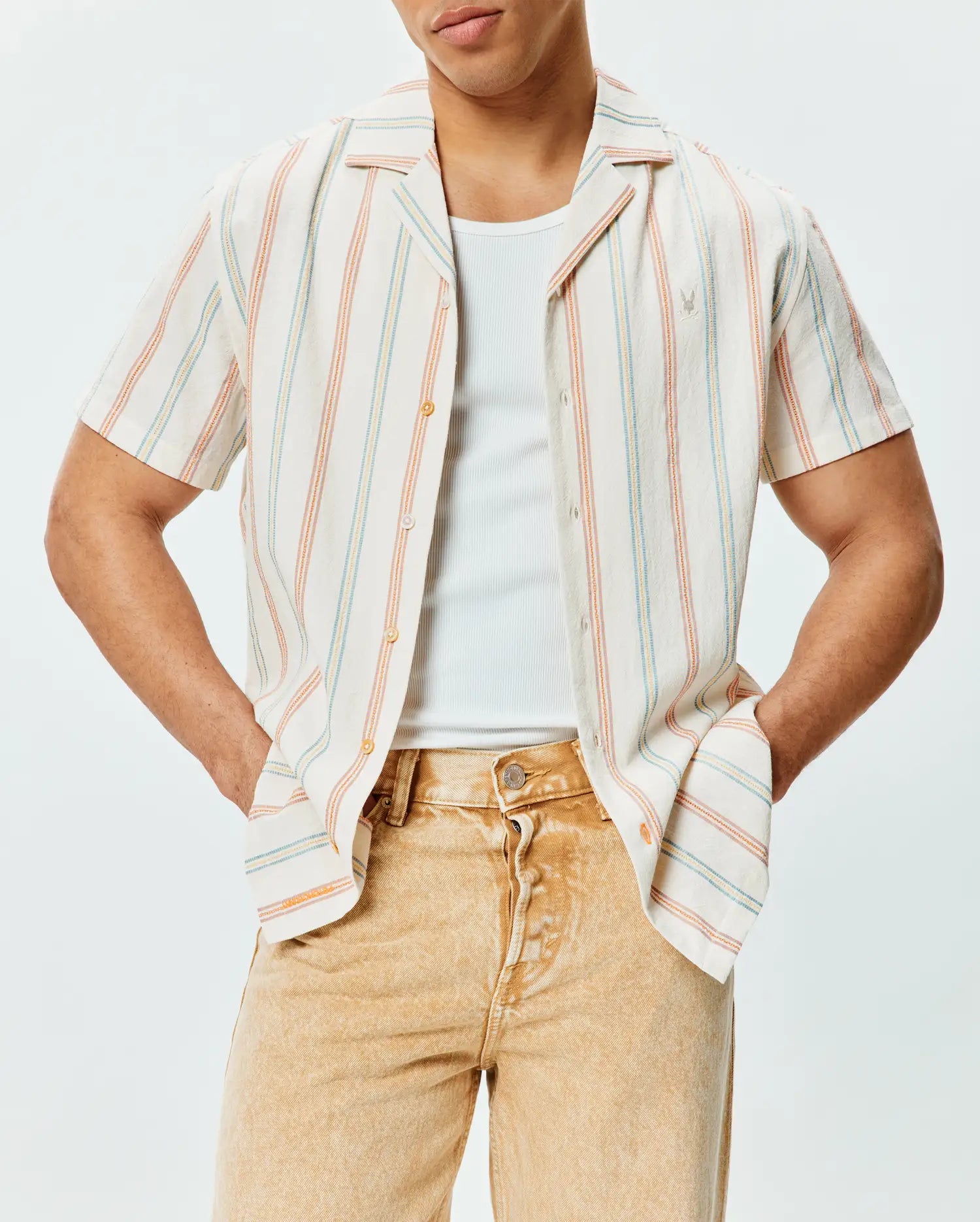 Mens Antoine Shirt, a relaxed fit cream short-sleeve button-up in textured slub fabric with vertical blue, orange, and yellow stripes, featuring a small embroidered Psycho Bunny logo on the left chest.