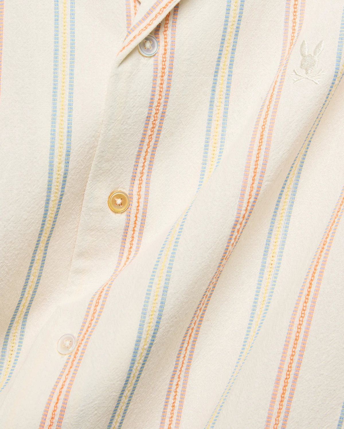 Mens Antoine Shirt, a cream textured woven shirt with vertical light blue, yellow, and orange stripes, featuring a small embroidered Psycho Bunny skull logo on the left chest.