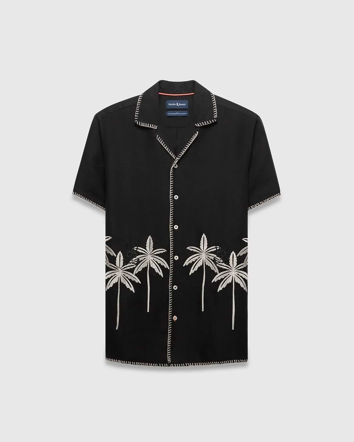 Mens Brad Linen Shirt, a black relaxed-fit camp collar shirt with white contrast stitching, embroidered light grey palm trees, and a small black Psycho Bunny skull logo.