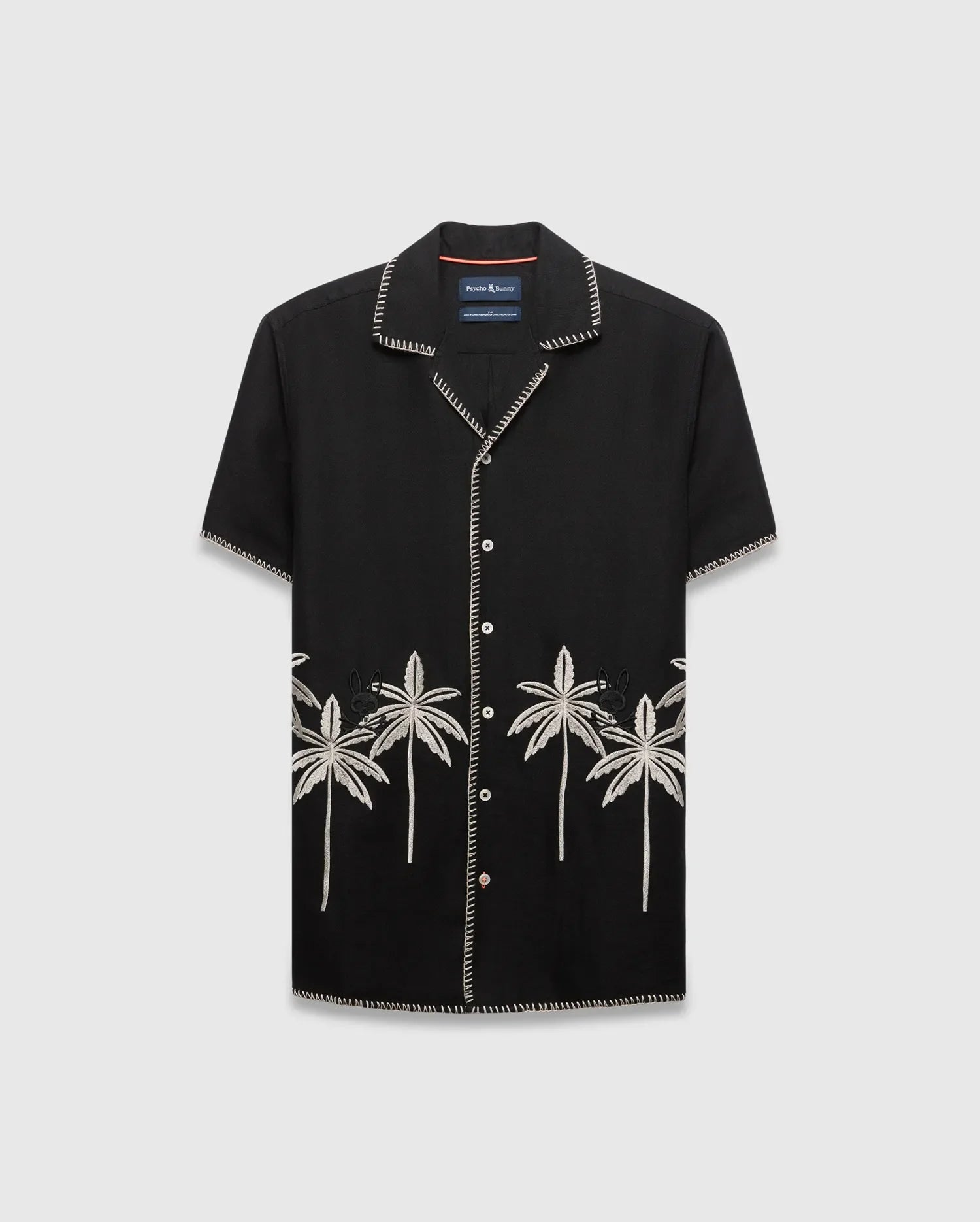 Mens Brad Linen Shirt, a black relaxed-fit camp collar shirt with white contrast stitching, embroidered light grey palm trees, and a small black Psycho Bunny skull logo.