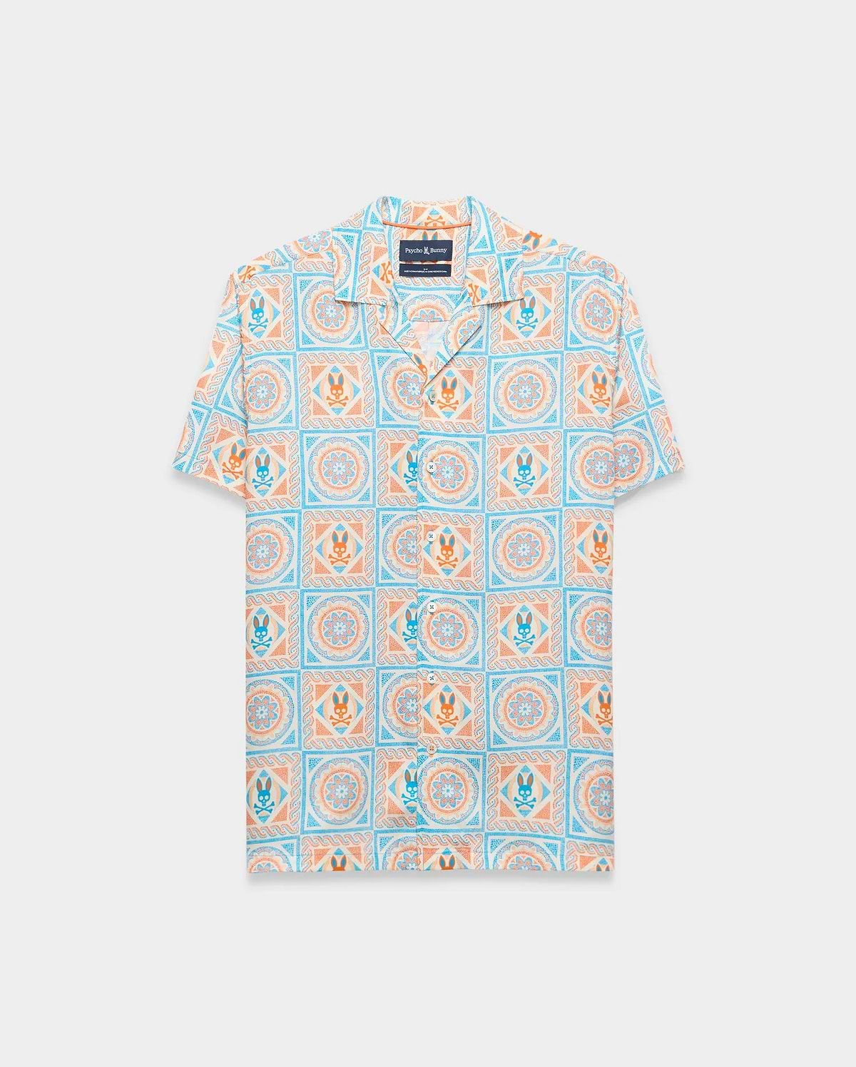 Mens Frank Tencel Shirt, a relaxed fit short-sleeve camp collar shirt in light blue, orange, and cream with an all-over tiled pattern featuring Psycho Bunny skull logos and floral designs.