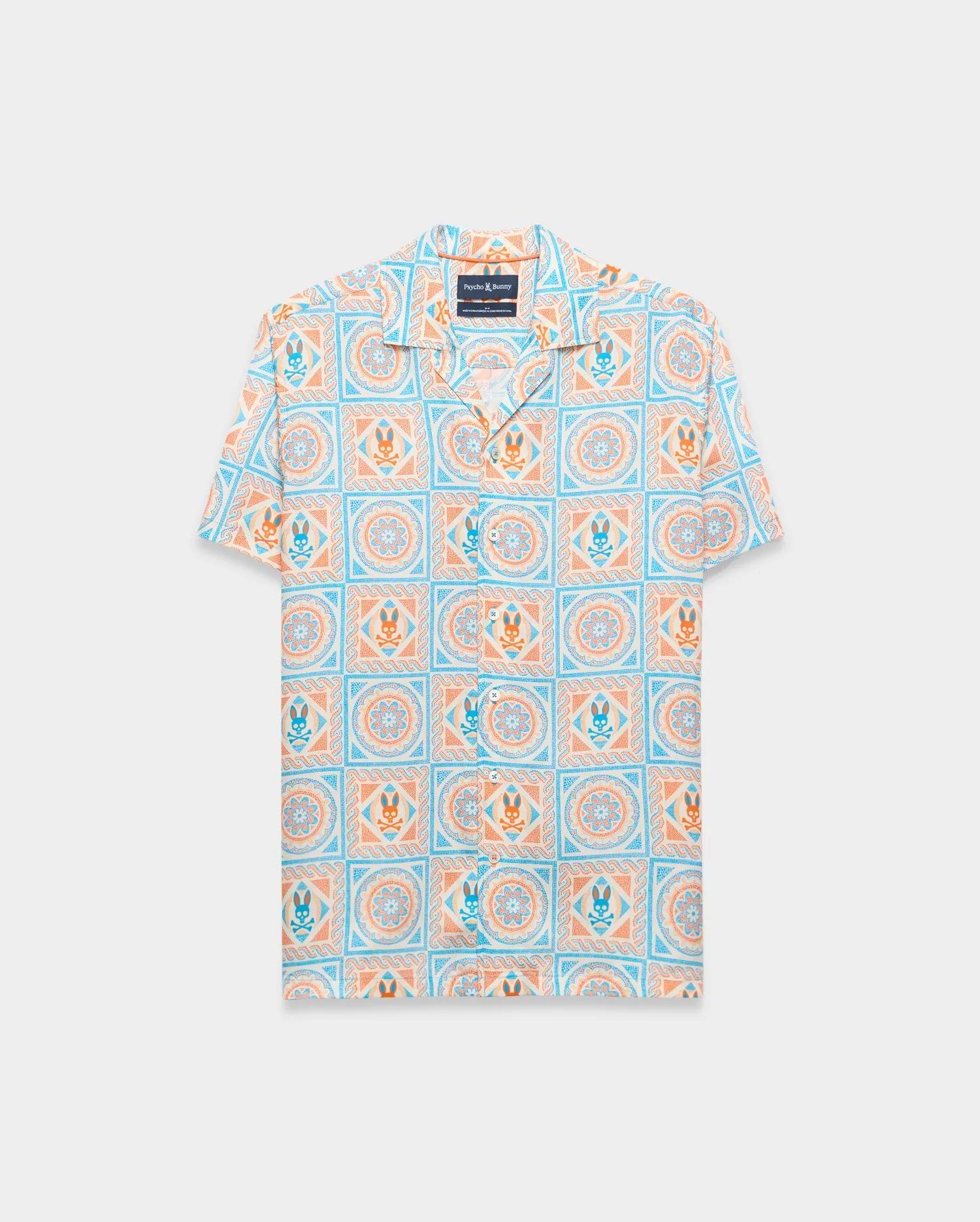 Mens Frank Tencel Shirt, a relaxed fit short-sleeve camp collar shirt in light blue, orange, and cream with an all-over tiled pattern featuring Psycho Bunny skull logos and floral designs.