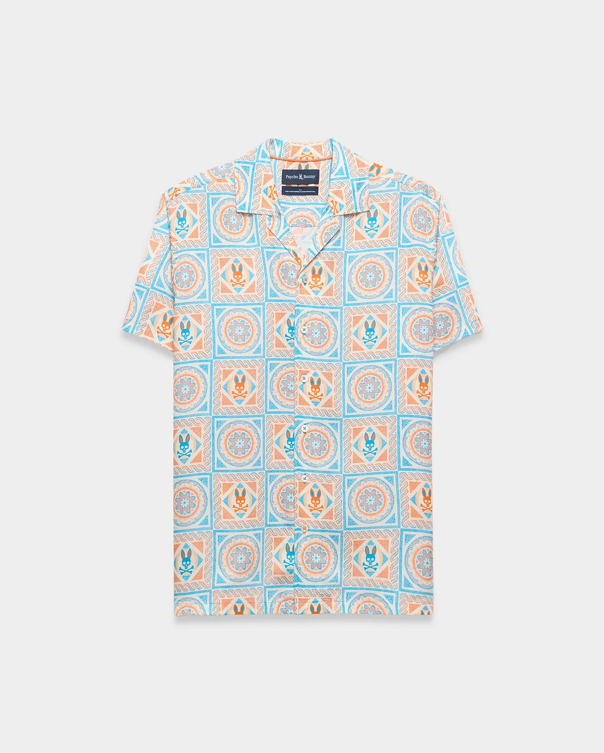 Mens Frank Tencel Shirt, a relaxed fit short-sleeve camp collar shirt in light blue, orange, and cream with an all-over tiled pattern featuring Psycho Bunny skull logos and floral designs.