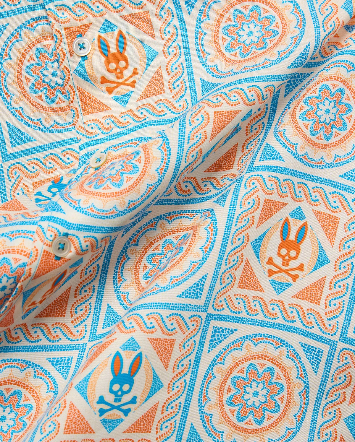 Mens Frank Tencel Shirt in cream with a vibrant orange and blue mosaic pattern, featuring the iconic Psycho Bunny skull logo and intricate floral designs.