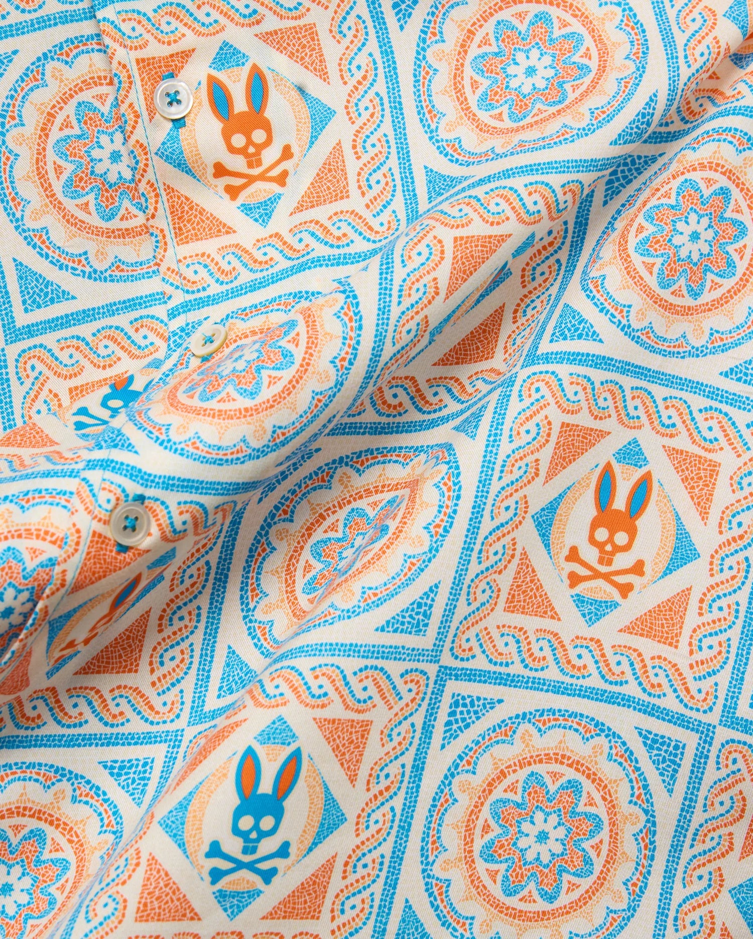 Mens Frank Tencel Shirt in cream with a vibrant orange and blue mosaic pattern, featuring the iconic Psycho Bunny skull logo and intricate floral designs.