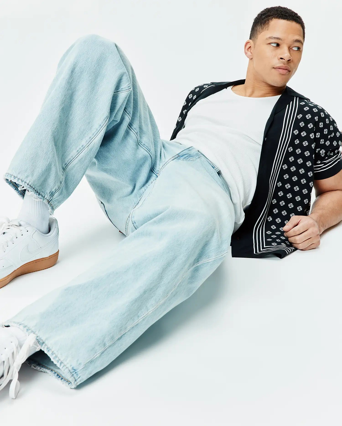 Mens Nick Tencel Shirt, a black relaxed-fit short-sleeve button-up featuring an allover white repeating Psycho Bunny skull logo pattern and vertical white stripes on the placket.