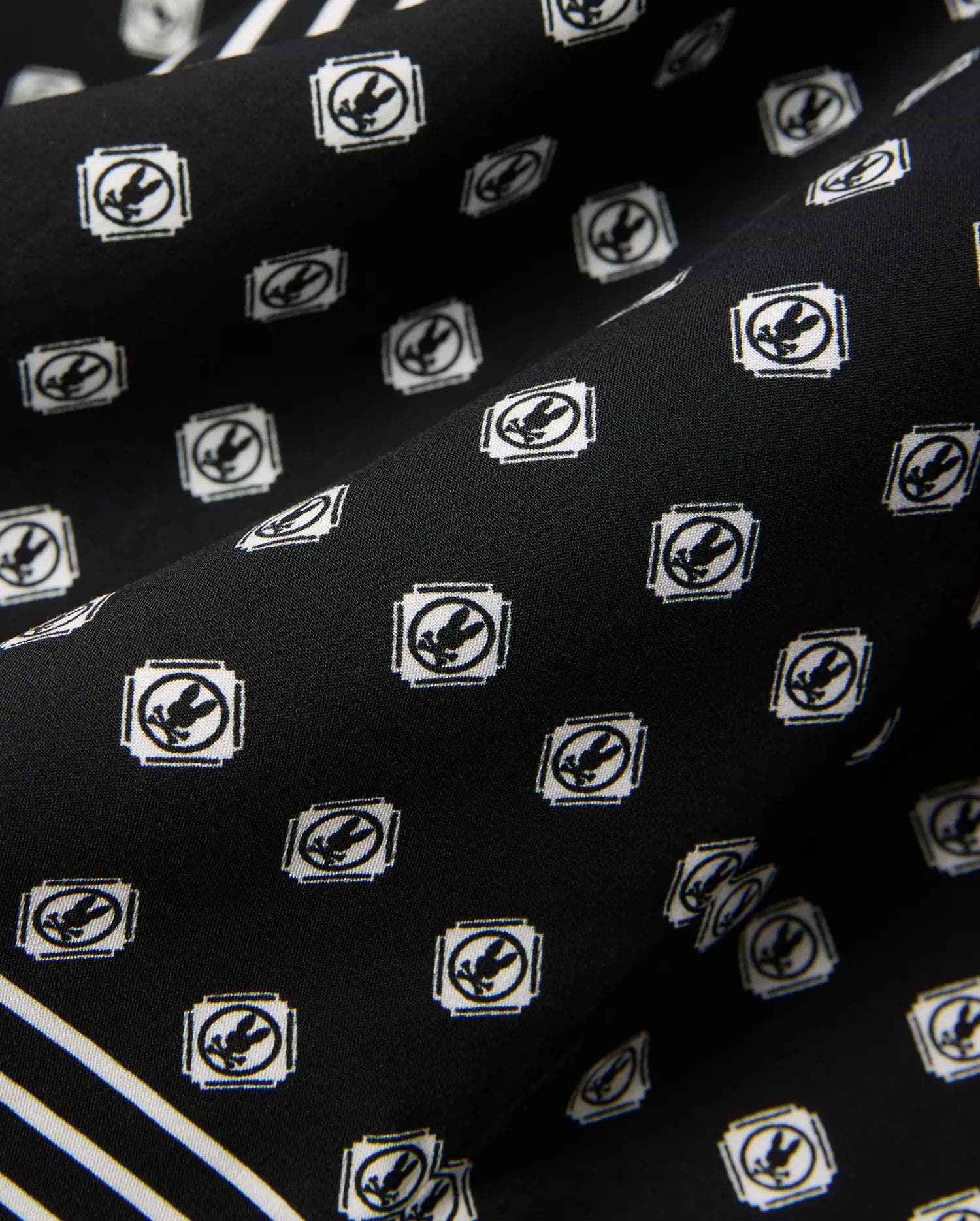 Mens Nick Tencel Shirt in black, featuring a white all-over Psycho Bunny skull logo pattern within square frames and white accent stripes on smooth tencel fabric.