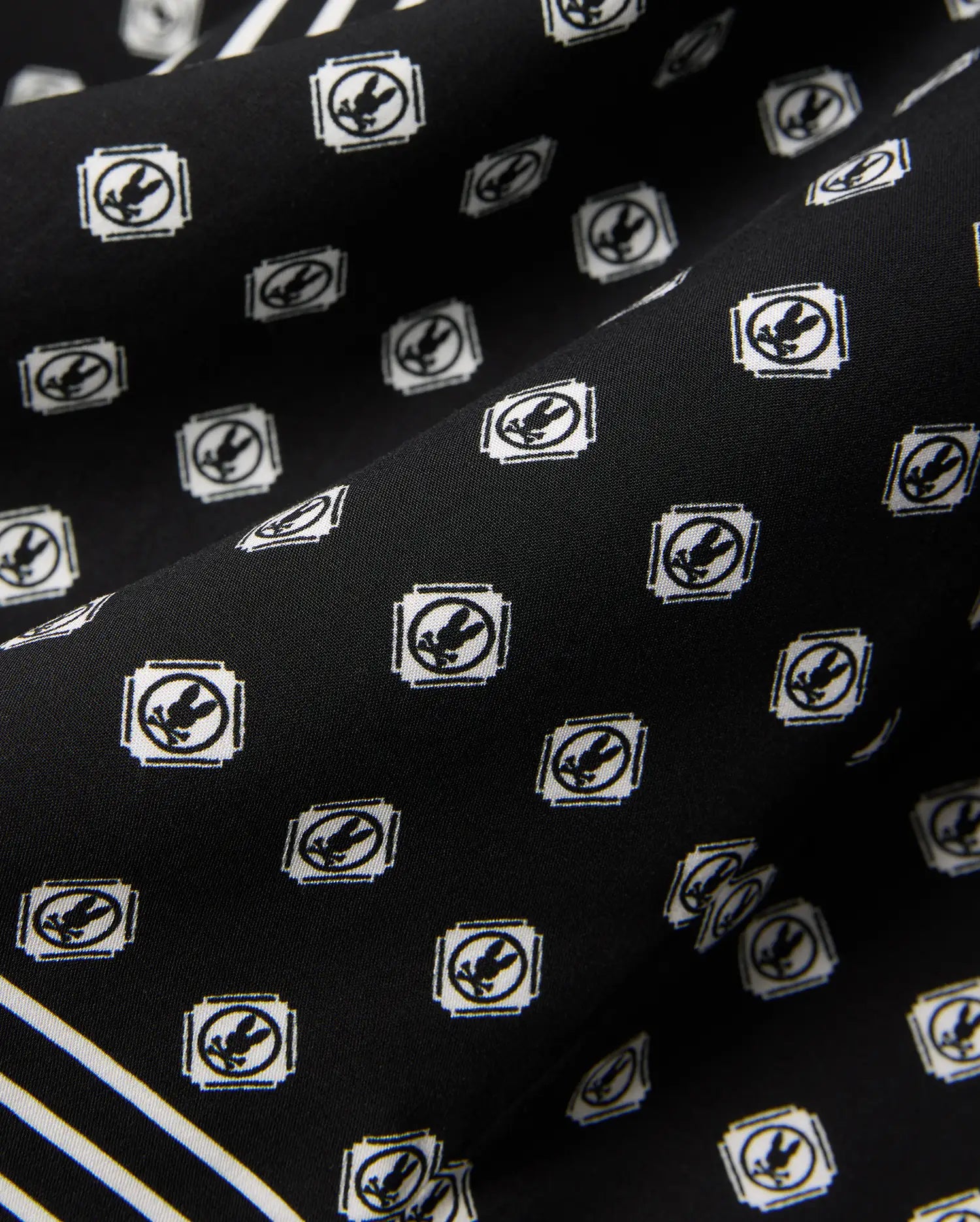 Mens Nick Tencel Shirt in black, featuring a white all-over Psycho Bunny skull logo pattern within square frames and white accent stripes on smooth tencel fabric.
