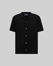 Mens Xandros Knit Shirt in black, featuring a classic fit, textured geometric knit fabric, a spread collar, full button-front with white buttons, and a small embroidered Psycho Bunny skull logo on the left chest.