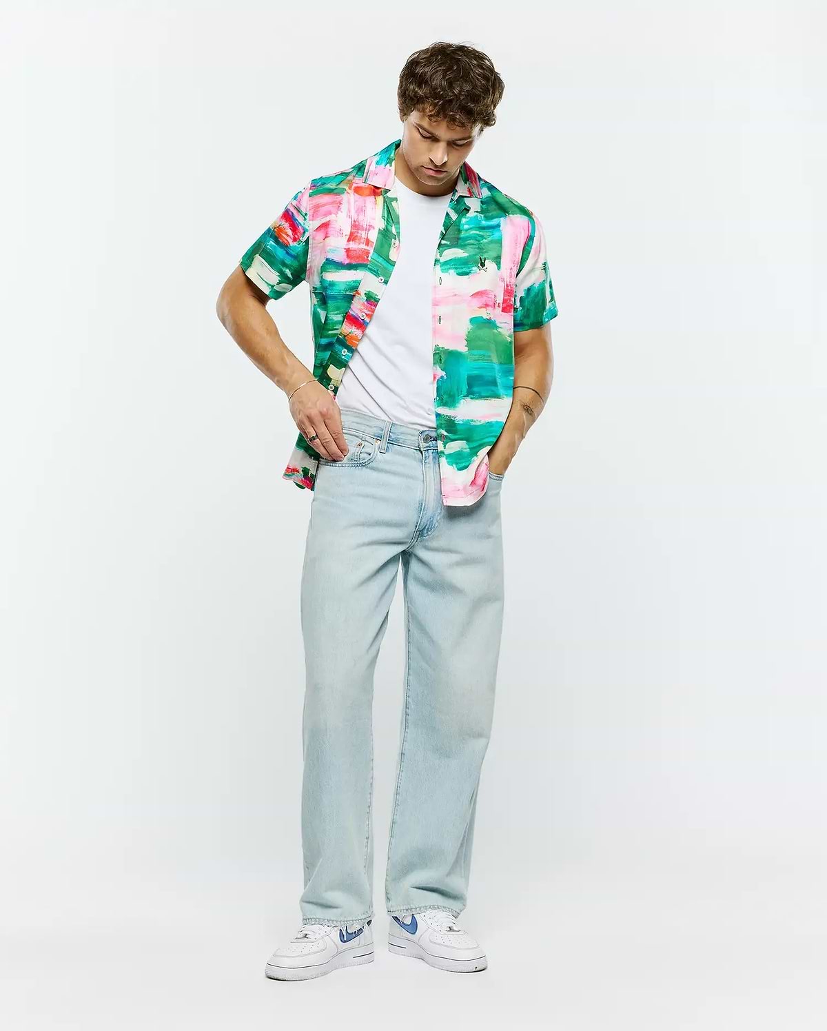 Psycho Bunny Mens Nate Tencel Shirt, a relaxed fit short-sleeve button-up with a vibrant abstract brushstroke pattern in pink, green, teal, and white, embodying refined streetwear.