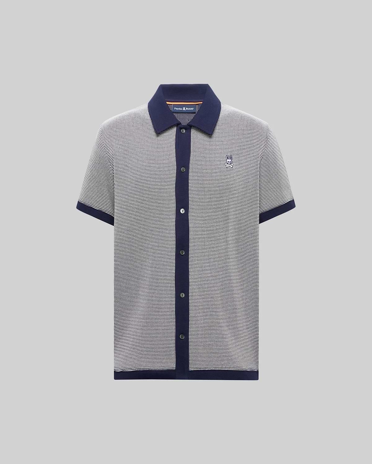 Mens Maxton Waffle Shirt, a classic fit short-sleeve knit polo in black and white micro-pattern with navy collar, placket, cuffs, and hem, featuring a small embroidered Psycho Bunny skull logo on the left chest.