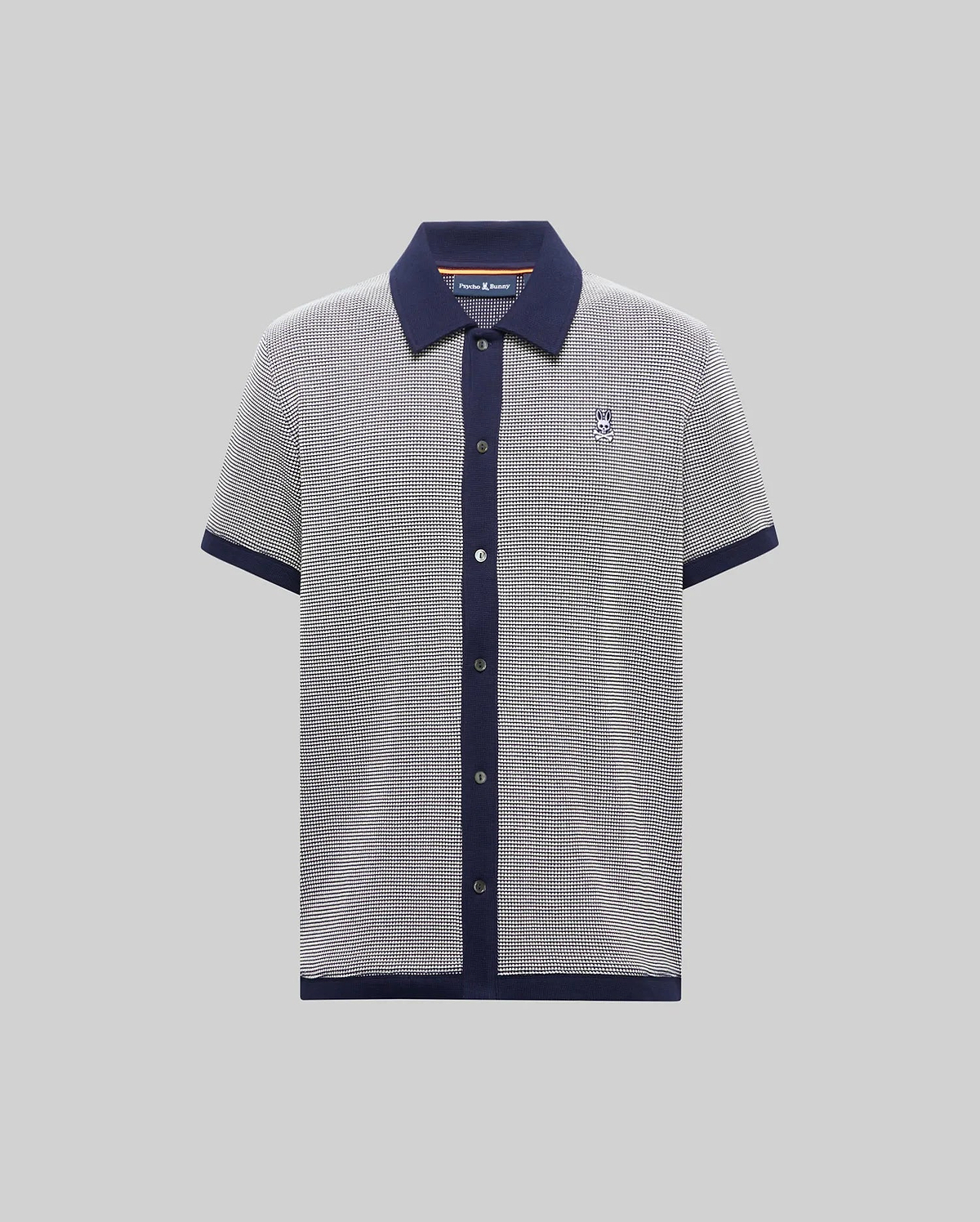 Mens Maxton Waffle Shirt, a classic fit short-sleeve knit polo in black and white micro-pattern with navy collar, placket, cuffs, and hem, featuring a small embroidered Psycho Bunny skull logo on the left chest.