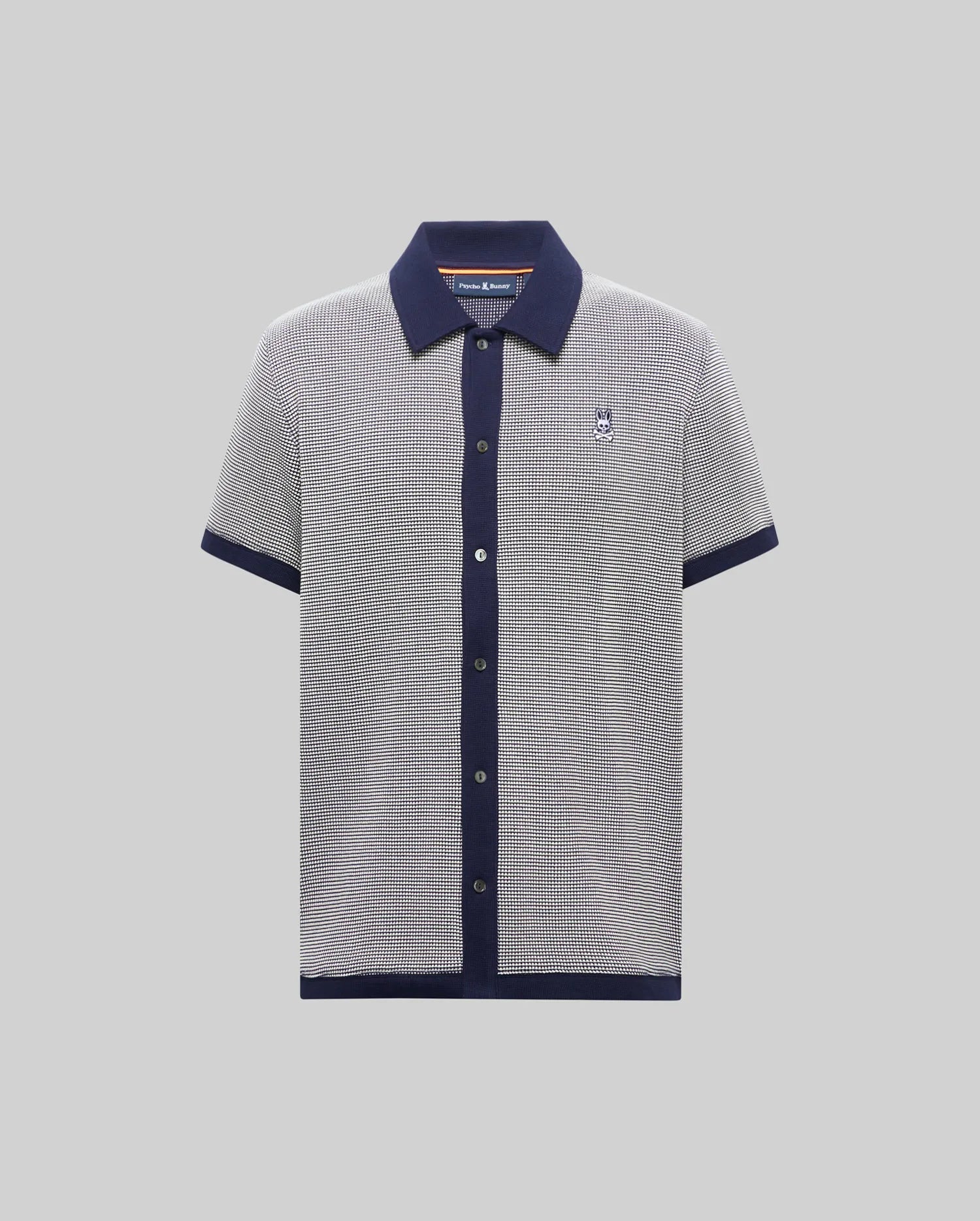 Mens Maxton Waffle Shirt, a classic fit short-sleeve knit polo in black and white micro-pattern with navy collar, placket, cuffs, and hem, featuring a small embroidered Psycho Bunny skull logo on the left chest.