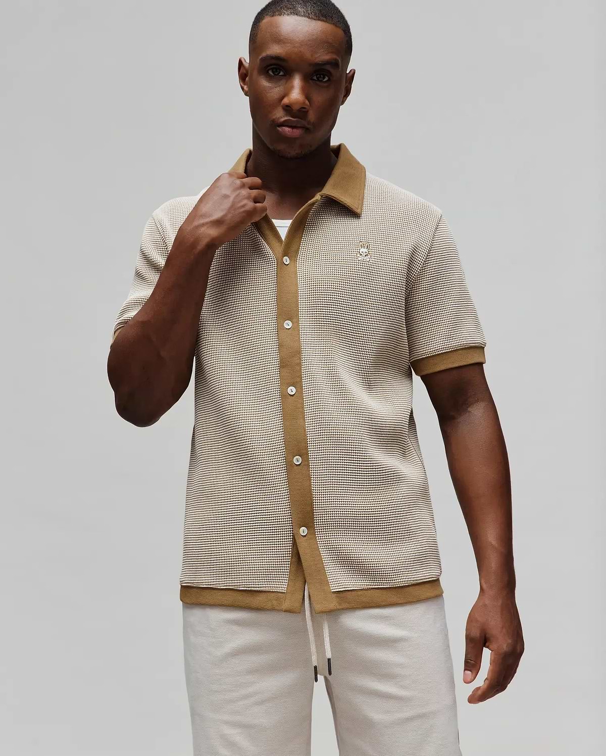 Mens Maxton Waffle Shirt, a classic fit short-sleeve button-up in cream and tan waffle knit, featuring a tan spread collar, full placket, and small embroidered Psycho Bunny skull logo on the left chest.