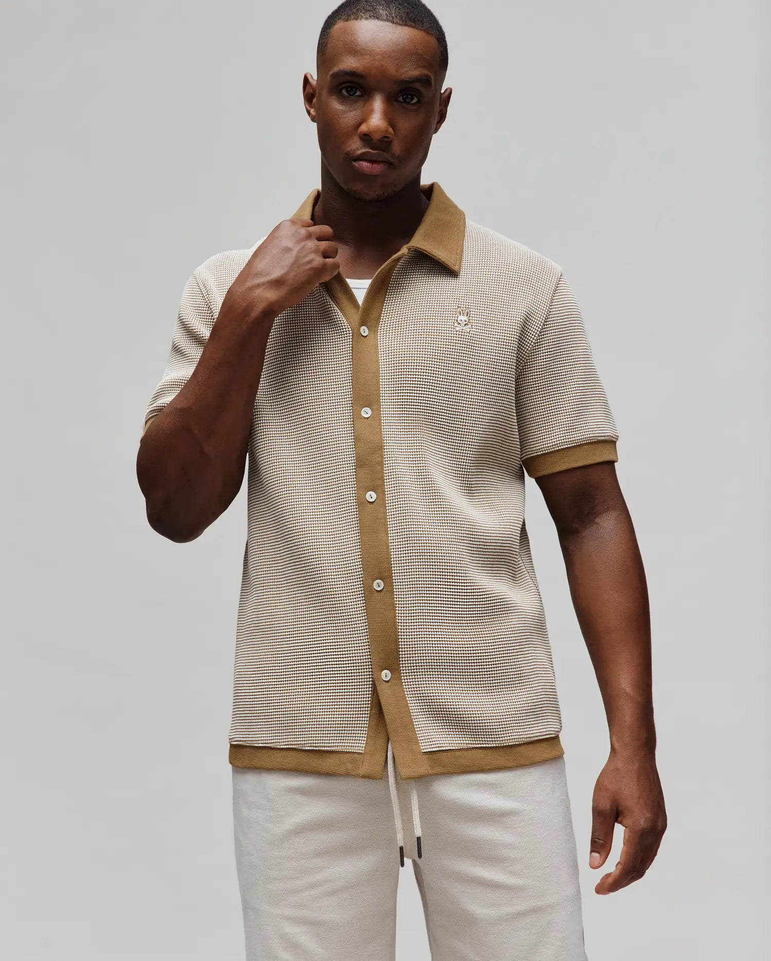 Mens Maxton Waffle Shirt, a classic fit short-sleeve button-up in cream and tan waffle knit, featuring a tan spread collar, full placket, and small embroidered Psycho Bunny skull logo on the left chest.
