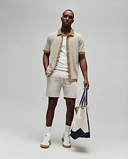 Mens Maxton Waffle Shirt, a relaxed fit beige waffle knit short-sleeve shirt with brown collar and placket, featuring a small embroidered Psycho Bunny logo on the left chest, paired with light beige drawstring shorts.