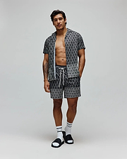 Black and white all-over Psycho Bunny skull logo pattern short-sleeve button-up shirt and matching shorts, both in a relaxed fit Tencel fabric with white drawstrings on the shorts. Mens Keon Tencel Shirt.