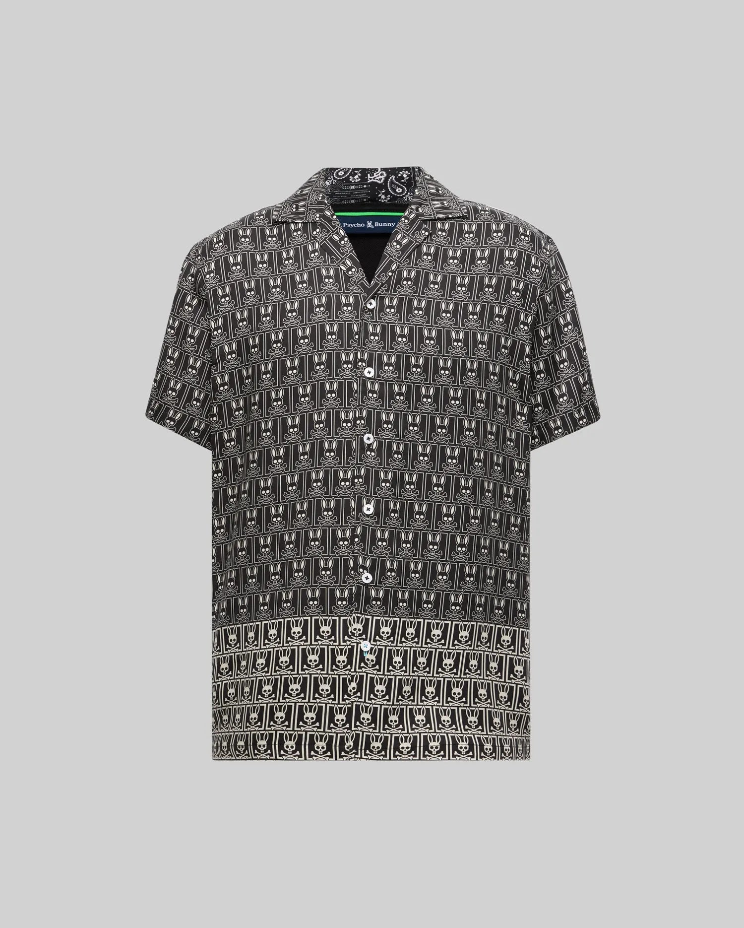 Mens Keon Tencel Shirt, a black short-sleeve button-up with a relaxed fit, featuring an all-over white Psycho Bunny skull logo pattern on smooth Tencel fabric, camp collar, and white buttons.